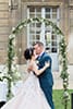 Les mariés s'embrassent sous une arche de fleurs