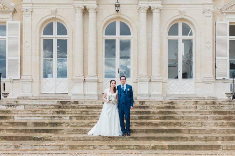 mariés se tenant la main devant le chateau d'AZY