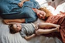 maman et son fils allonges sur le lit pendant une seance famille