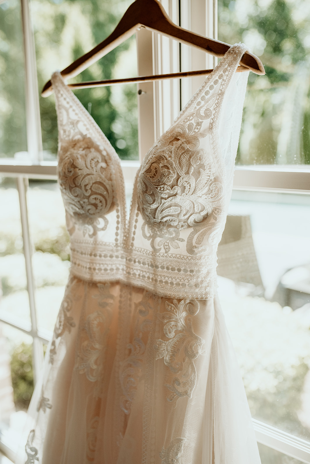 boho style wedding dress hanging in front of window