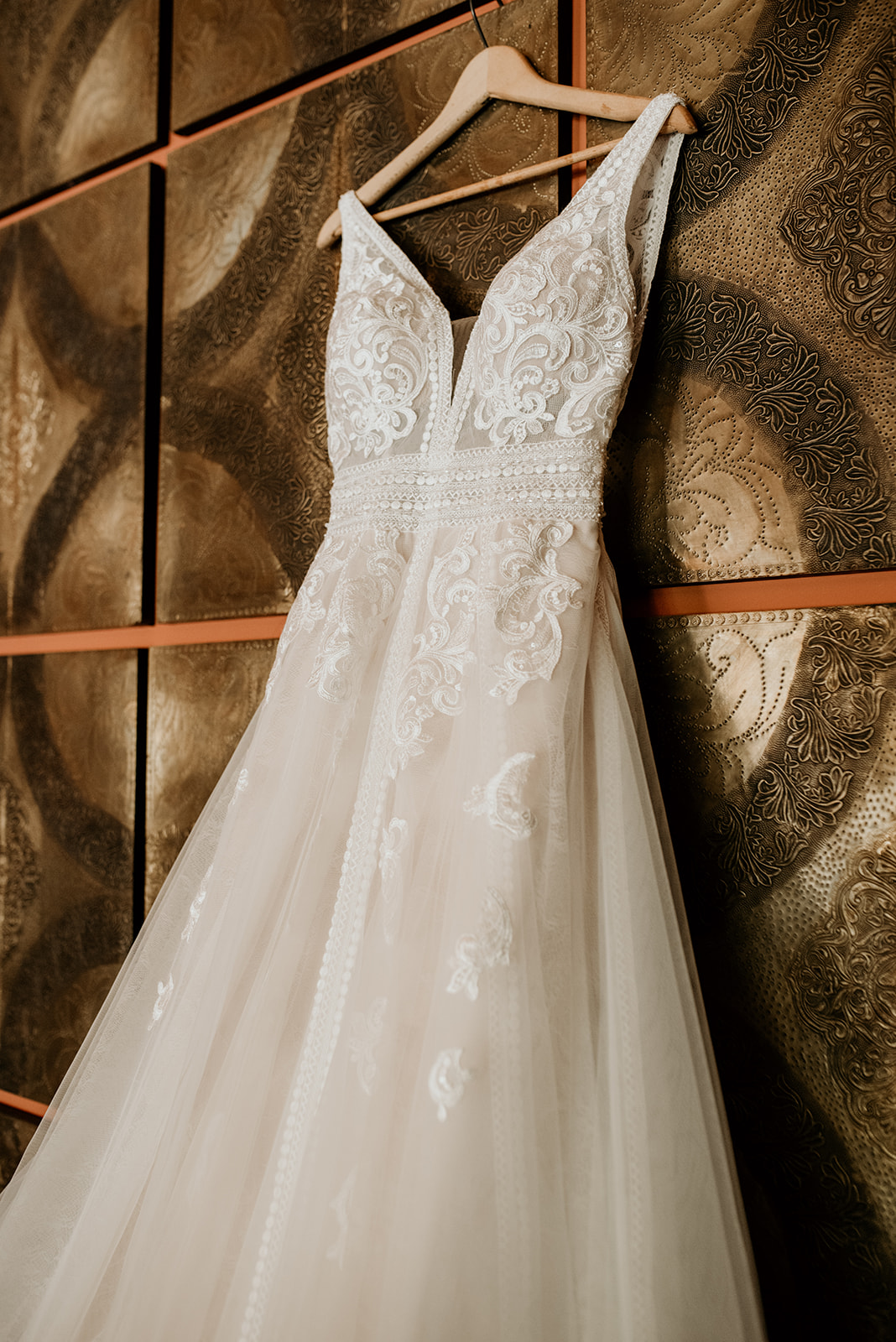 boho style wedding dress hanging on metallic tile wall