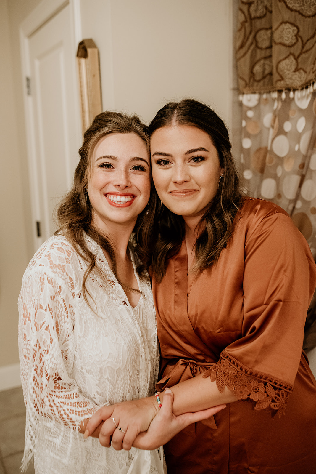 bride with maid of honor in robes befoe getting dressed for wedding