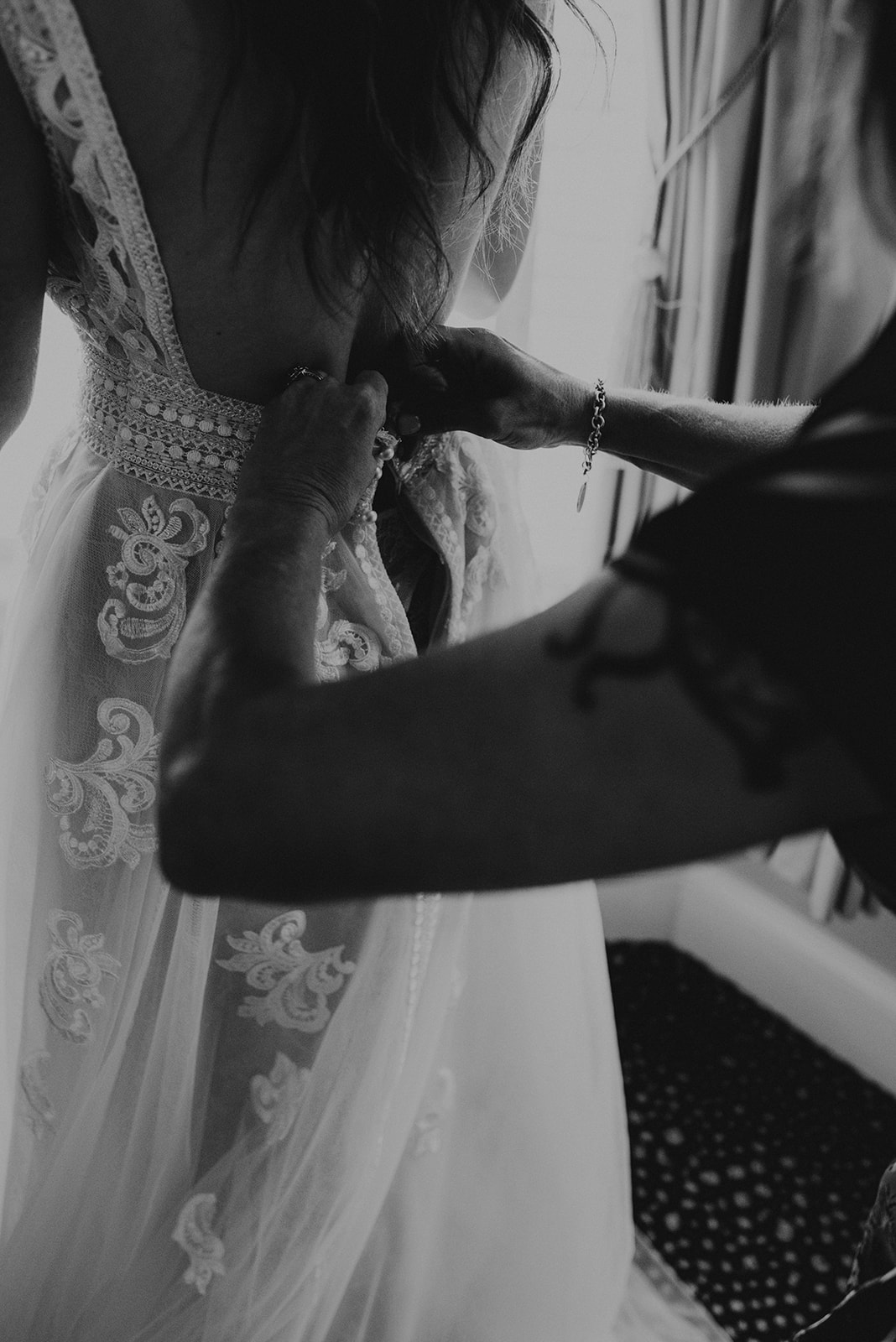 mother of the bride buttoning brides wedding dress