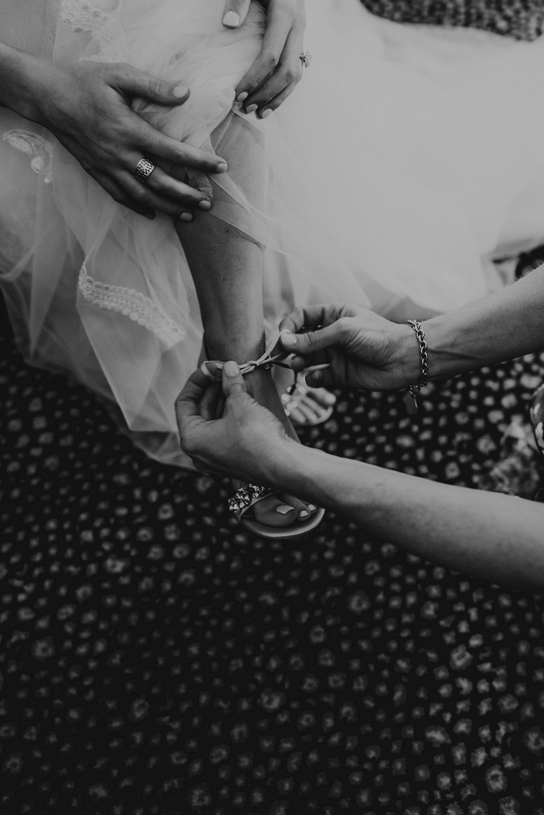 mother of bride helping bride put her wedding shoes on