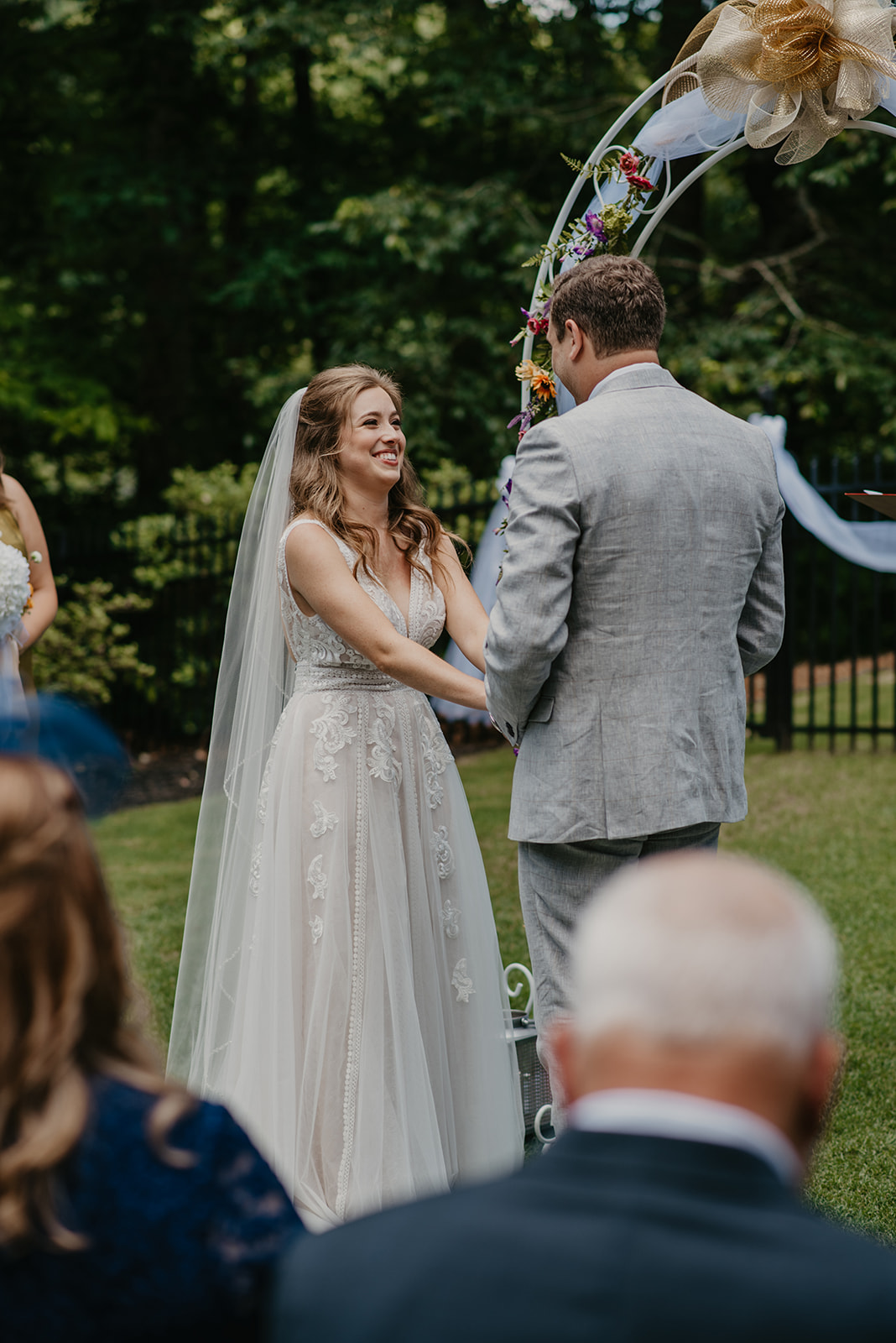 bride holding hands with groom at altar and smiling