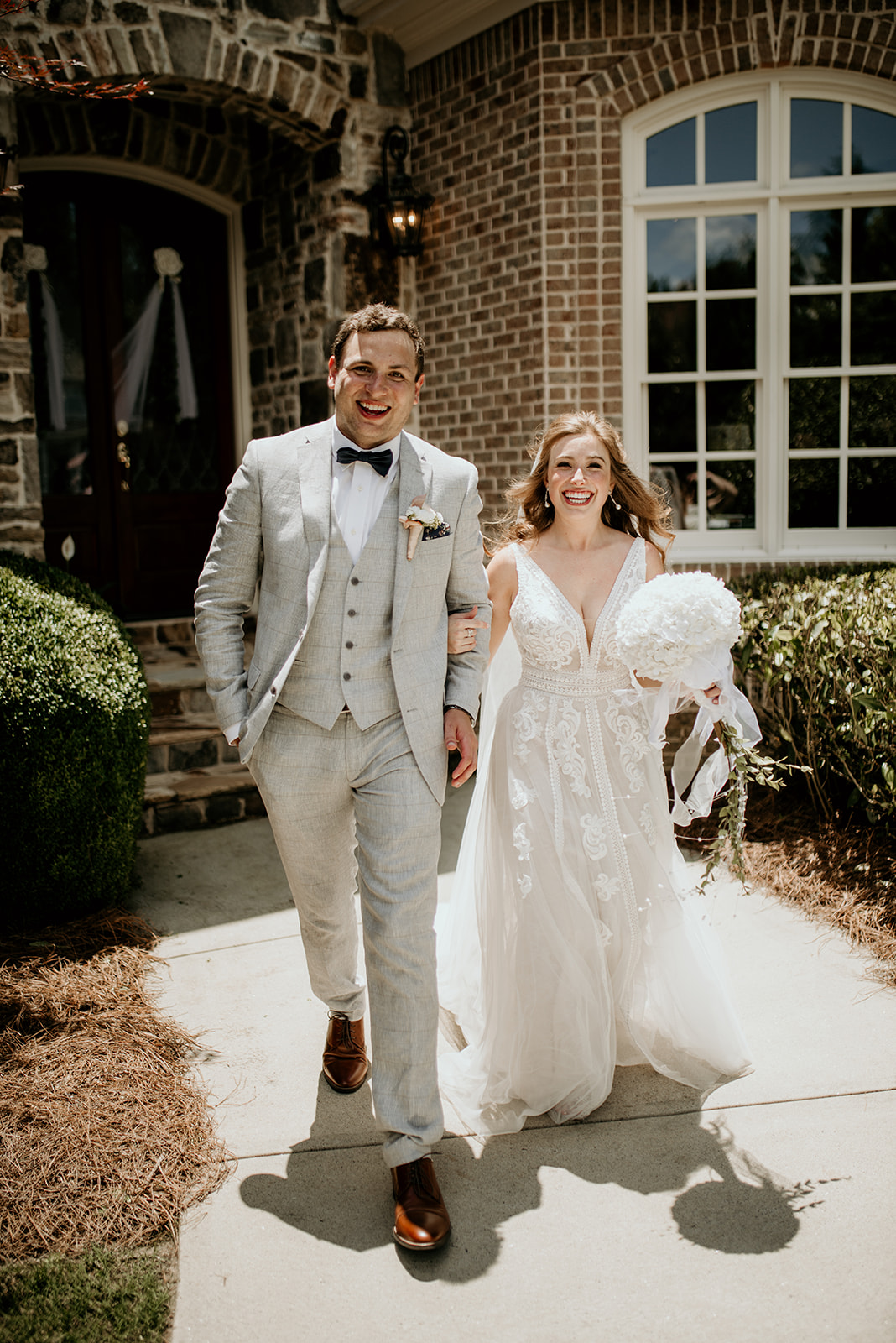 groom and bride walking out of house smiling