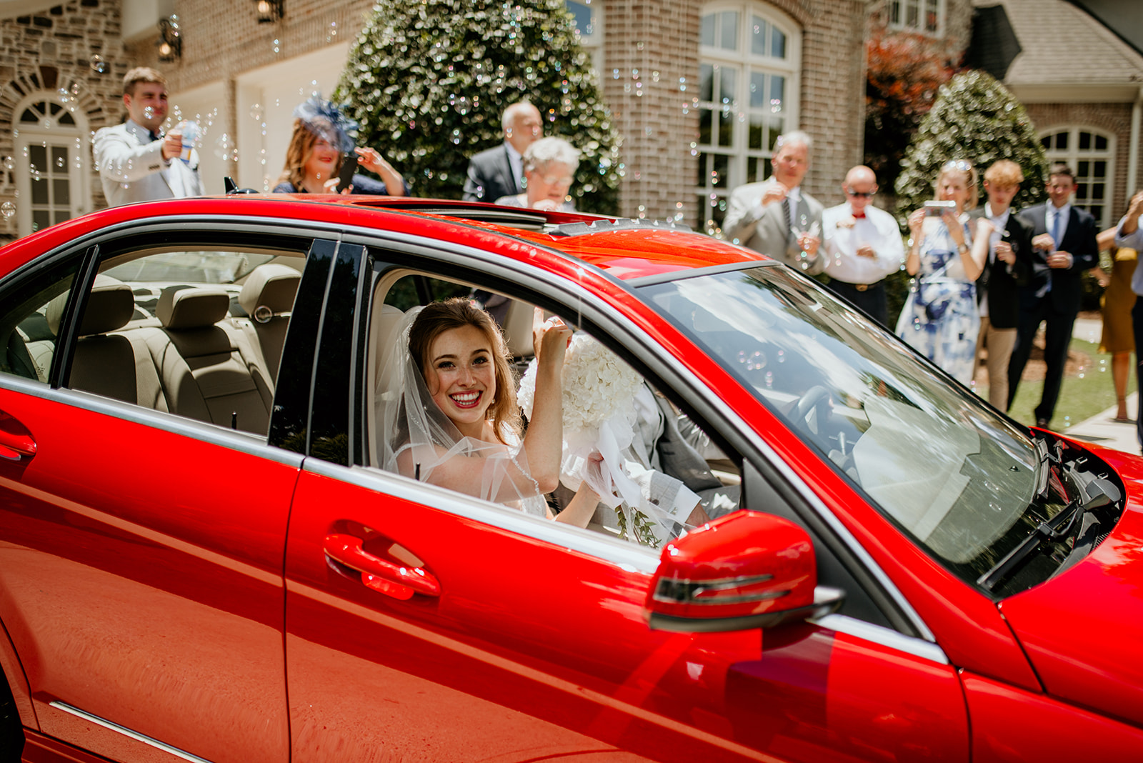 bride and groom in red getaway car
