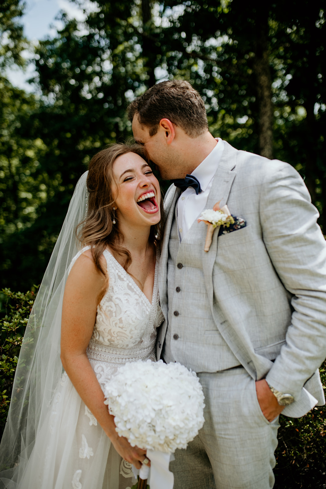 groom whispering in brides ear while she laughs