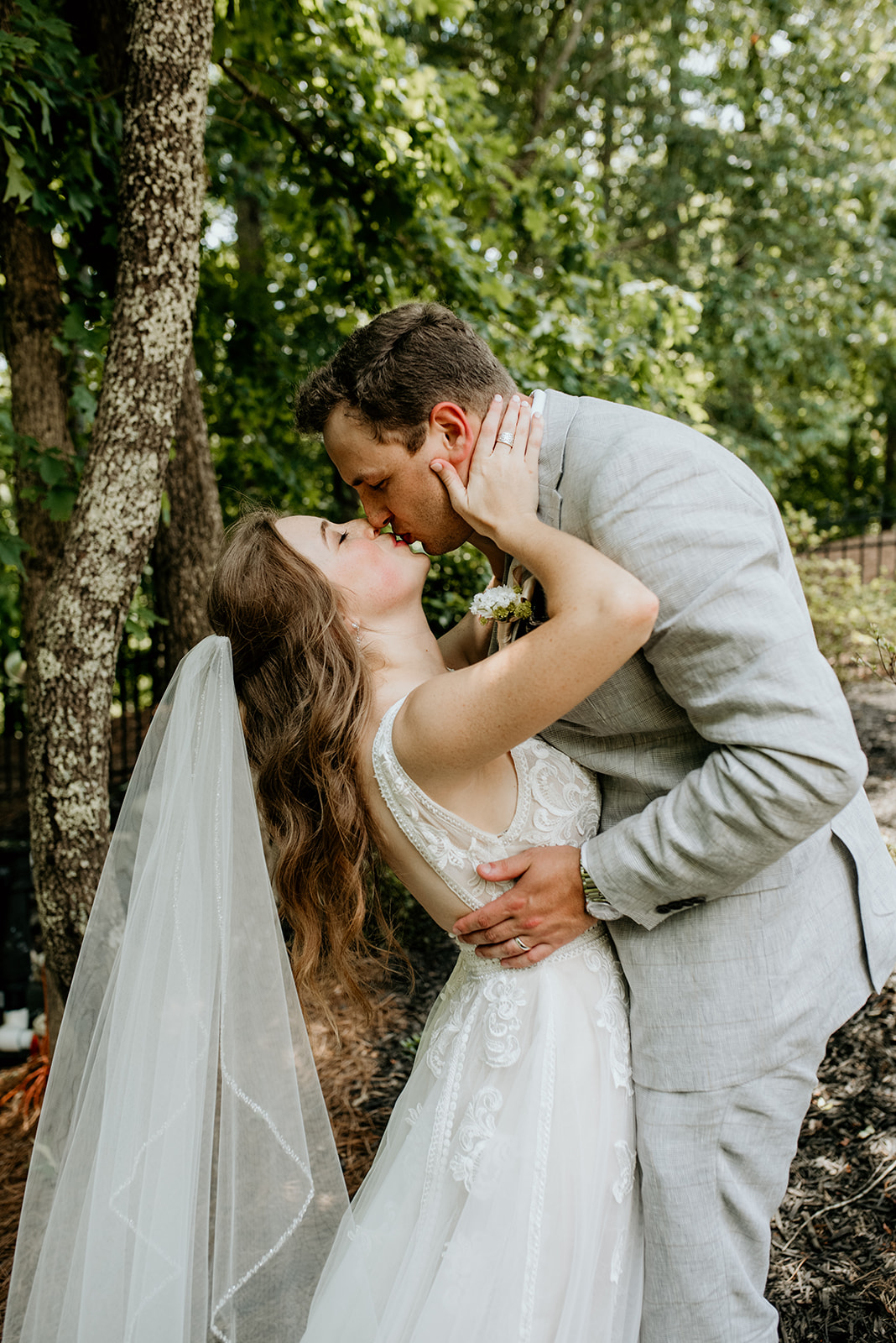 bride and groom kissing while bride holds grooms face