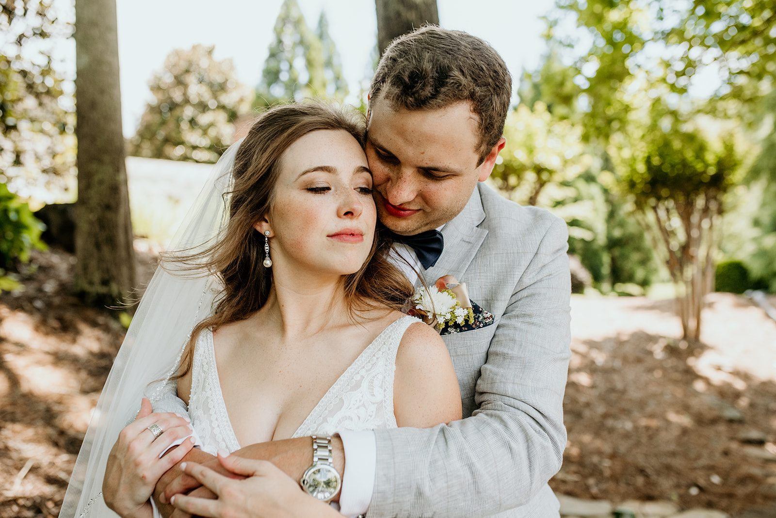 groom with his arms around bride, groom looking down and bride has eyes closed