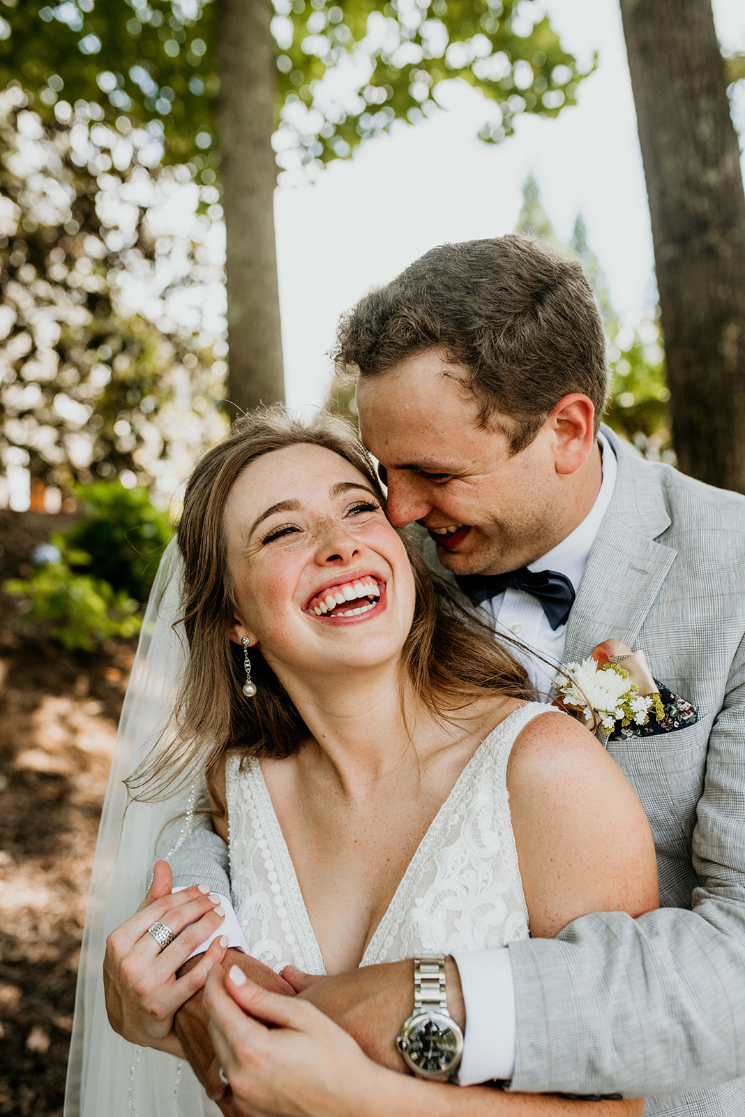 groom with arms around bride, both laughing