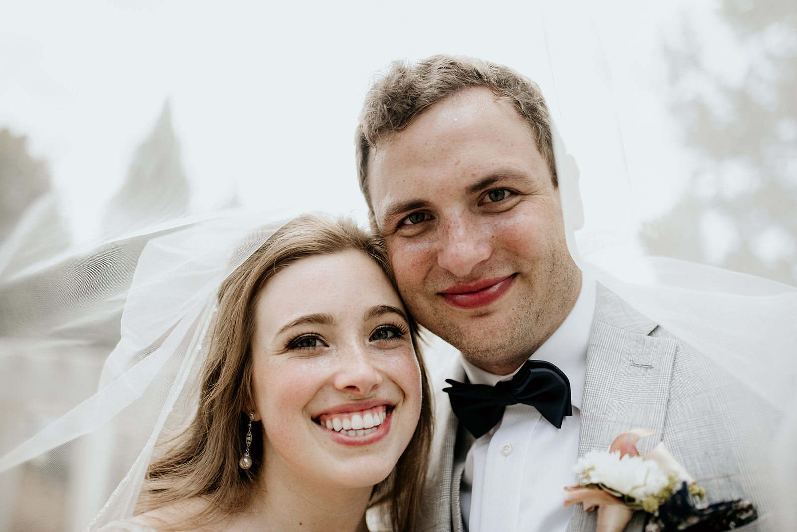 bride and groom under veil smiling