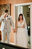 bride and groom on each side of a door holding hands and bride reading vows while groom wipes tears from his eyes