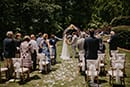bride and groom holding hands at altar in outdoor wedding with guests looking on
