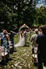 groom kissing bride in front of outdoor arbor with guests looking on
