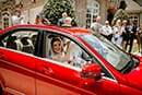 bride and groom in red getaway car
