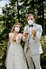 bride and groom with n95 masks on. holding corona beers and holding up ring fingers