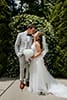 bride and groom kissing in front of an ivy archway