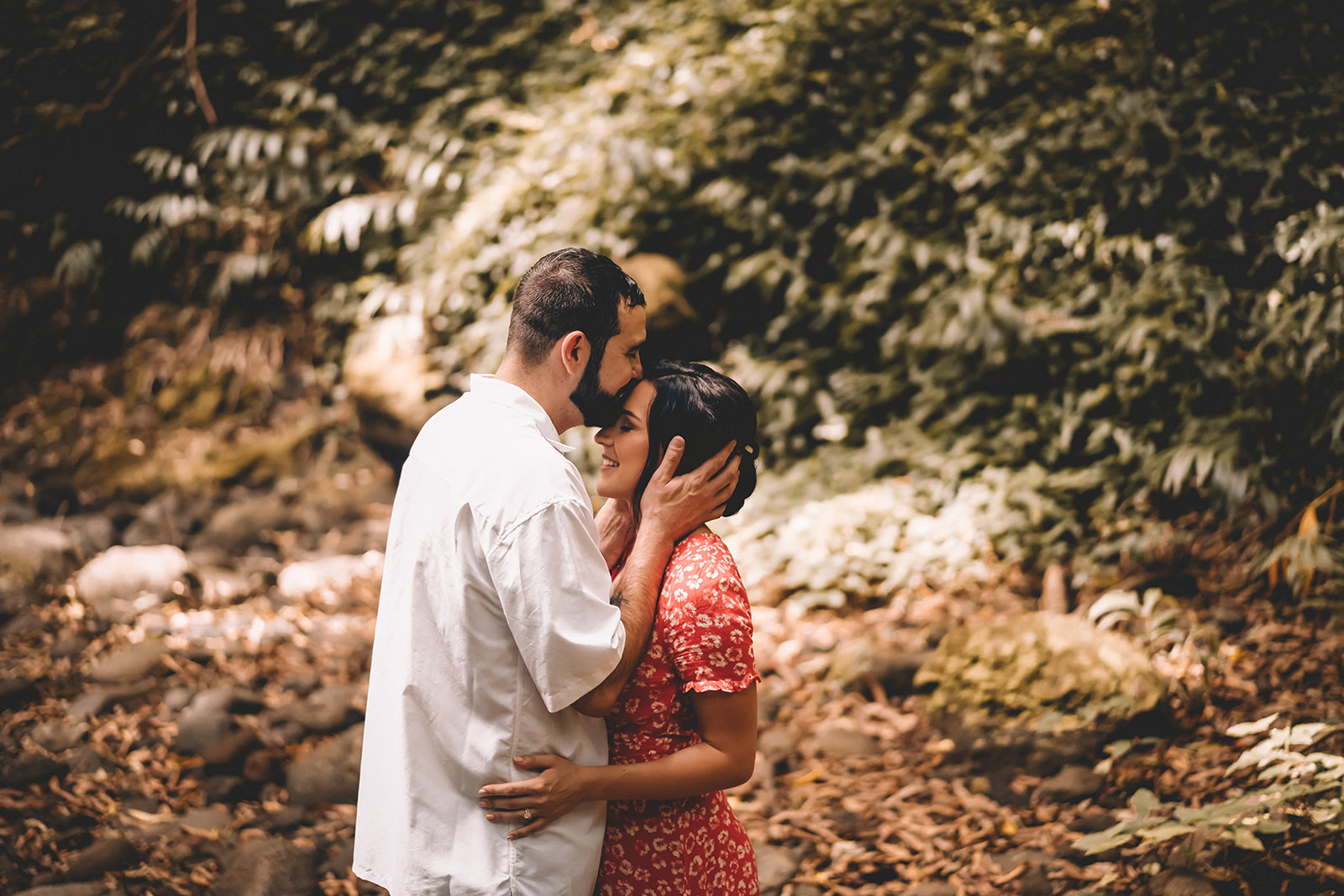 Man kissing womans forehead during engagement photoshoot in forest