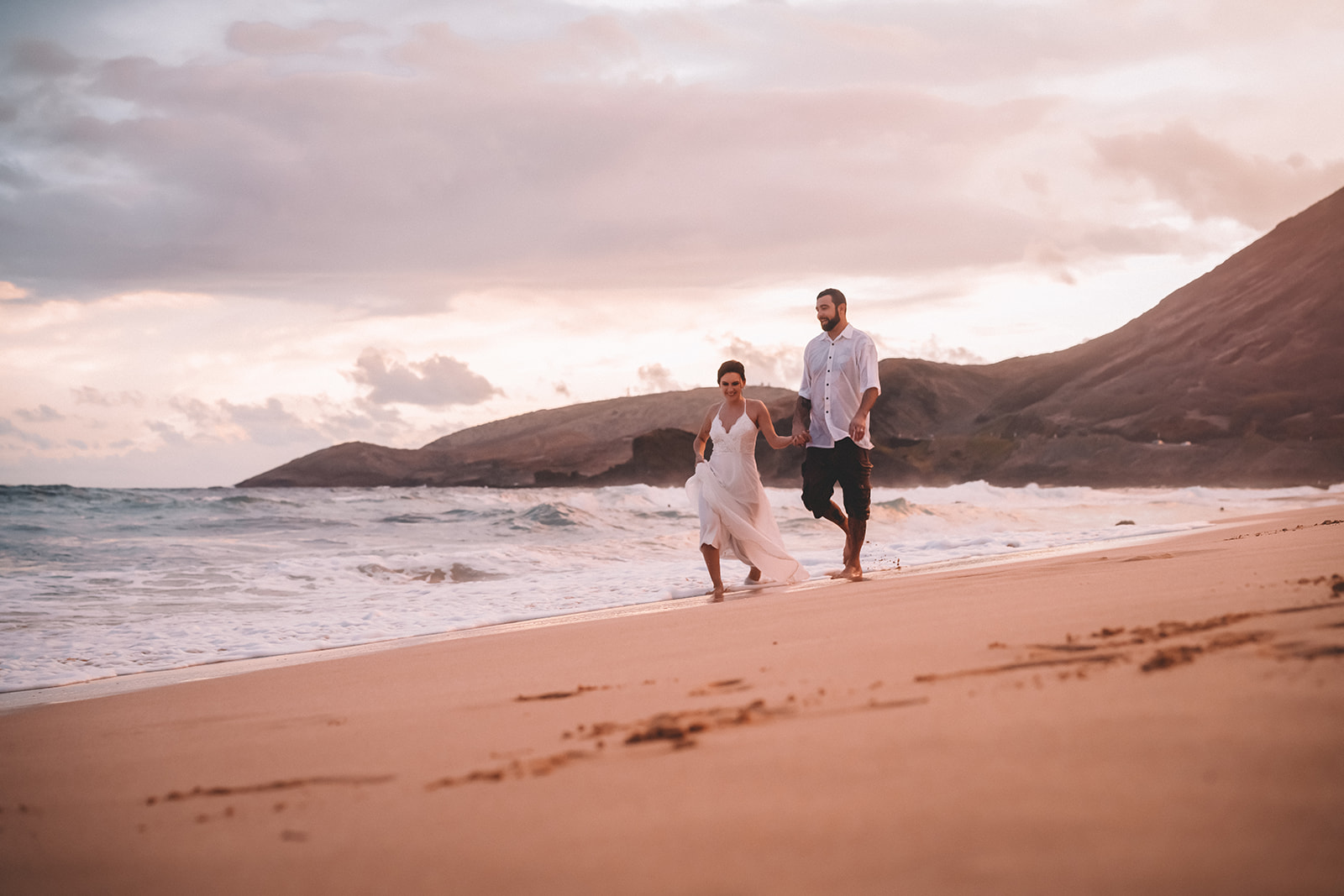 newlywed husband and wife walking along Hawaii beach