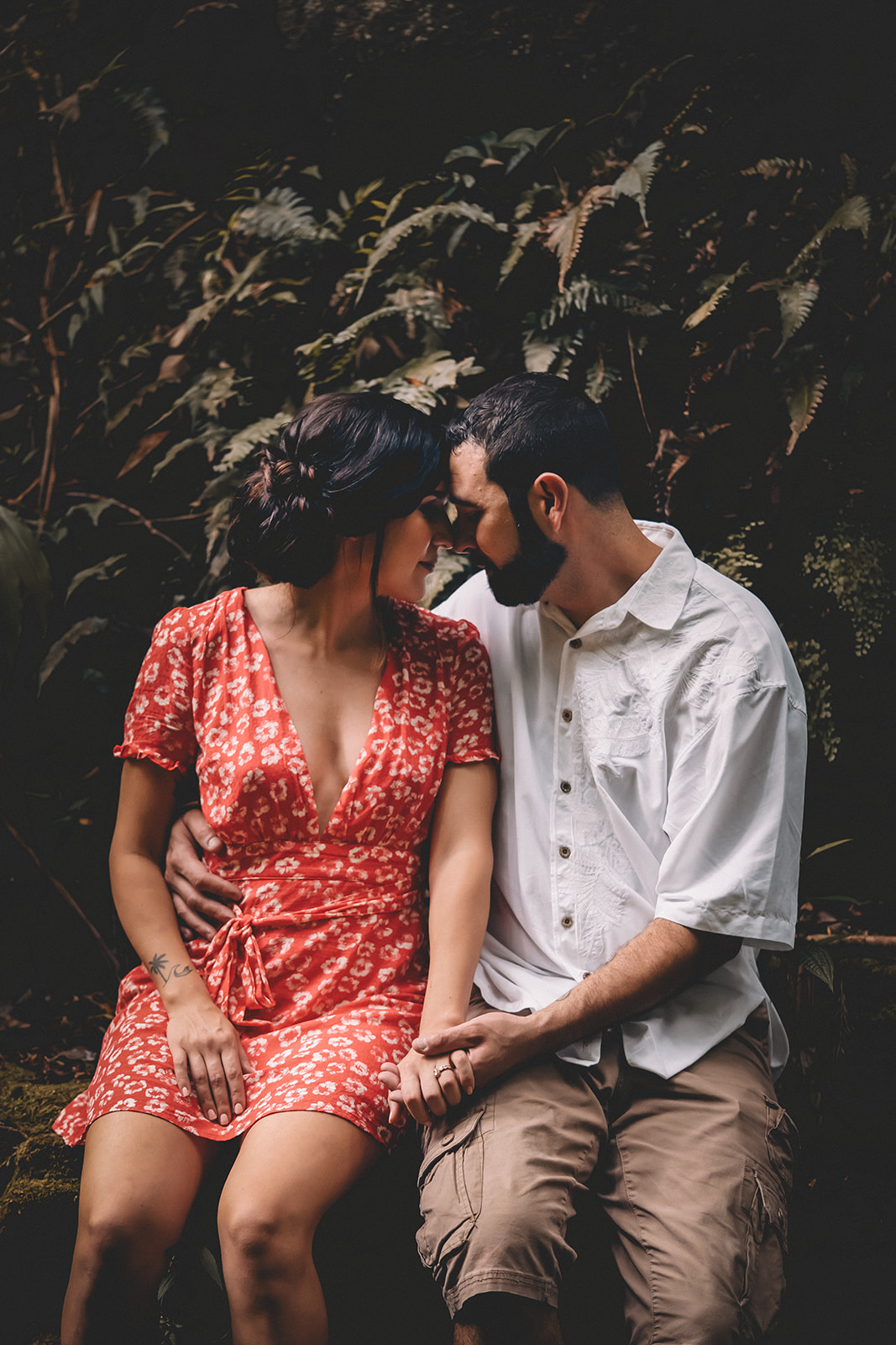 man resting forehead and holding hand woman in red dress Ka'au Crater Trail