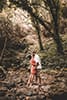 Woman in red dressing kissing boyfriend in Hawaii forest during couples photoshoot