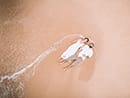 bride and groom holding hands laying on beach aerial drone shot