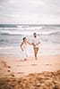 newlywed bride and groom walking away from ocean Hawaii beach