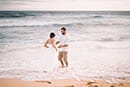 bride and groom standing on shoreline in water