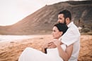husband hugging wife from behind sitting on Hawaii beach