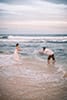newlywed husband and wife playing in Hawaii ocean