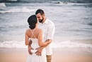 groom holding wife white sand beach Hawaii