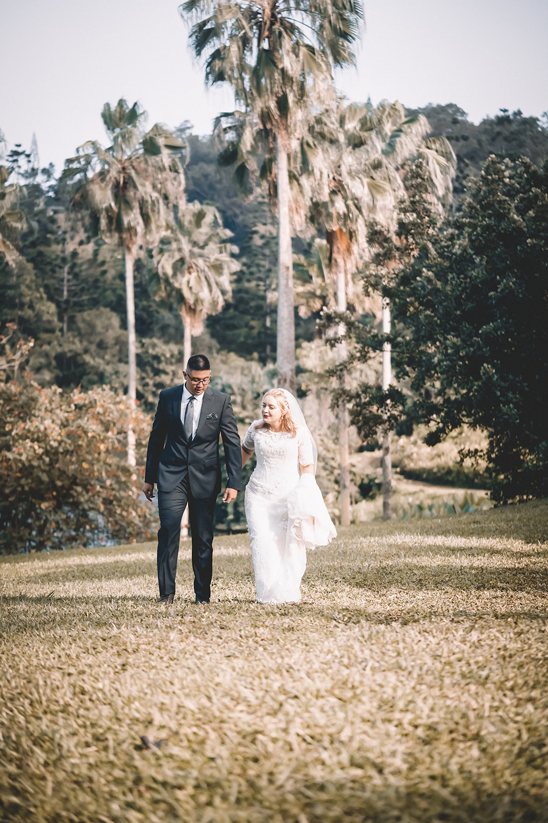 Bride and groom to be holding hands walking hoomaluhia botanical garden