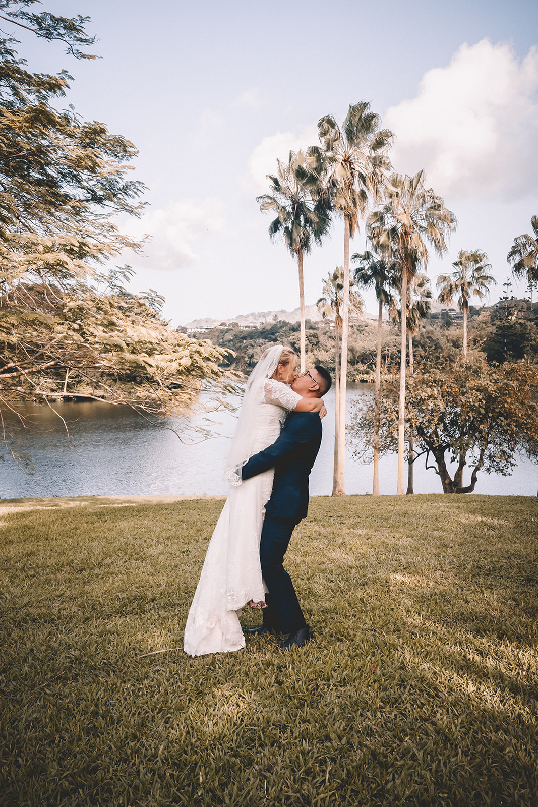 Groom holding and kissing bride to be hoomaluhia botanical garden Hawaii