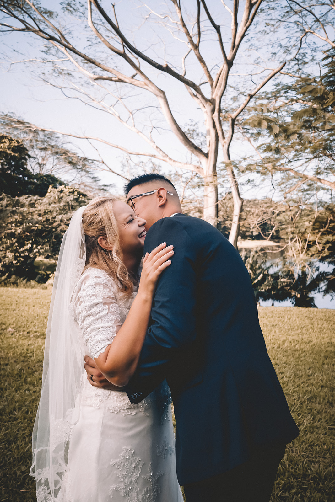 Groom kissing bride to be giggling hoomaluhia botanical garden