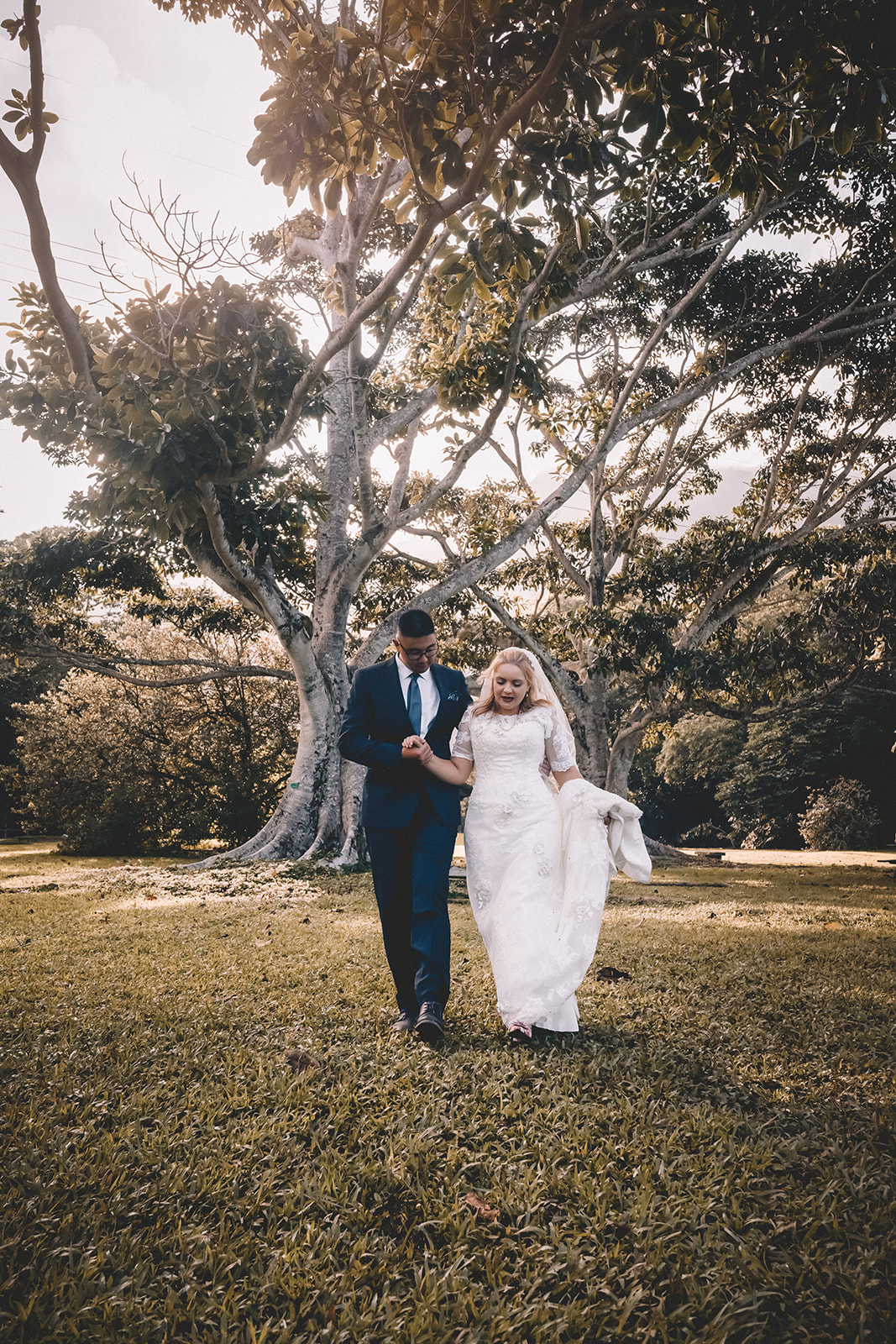 Bride and groom walking holding hands hoomaluhia botanical garden