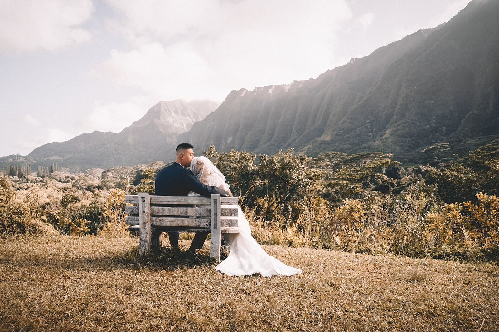 bride and groom sitting on bench staring into distance hoommaluhia botanical garden