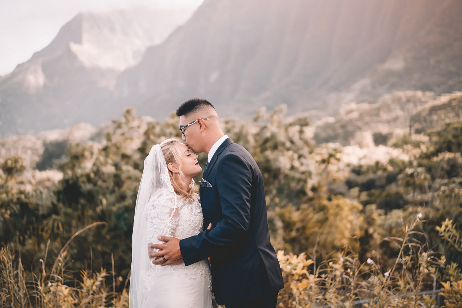 man kissing bride to be's forehead hoomaluhia botanical garden
