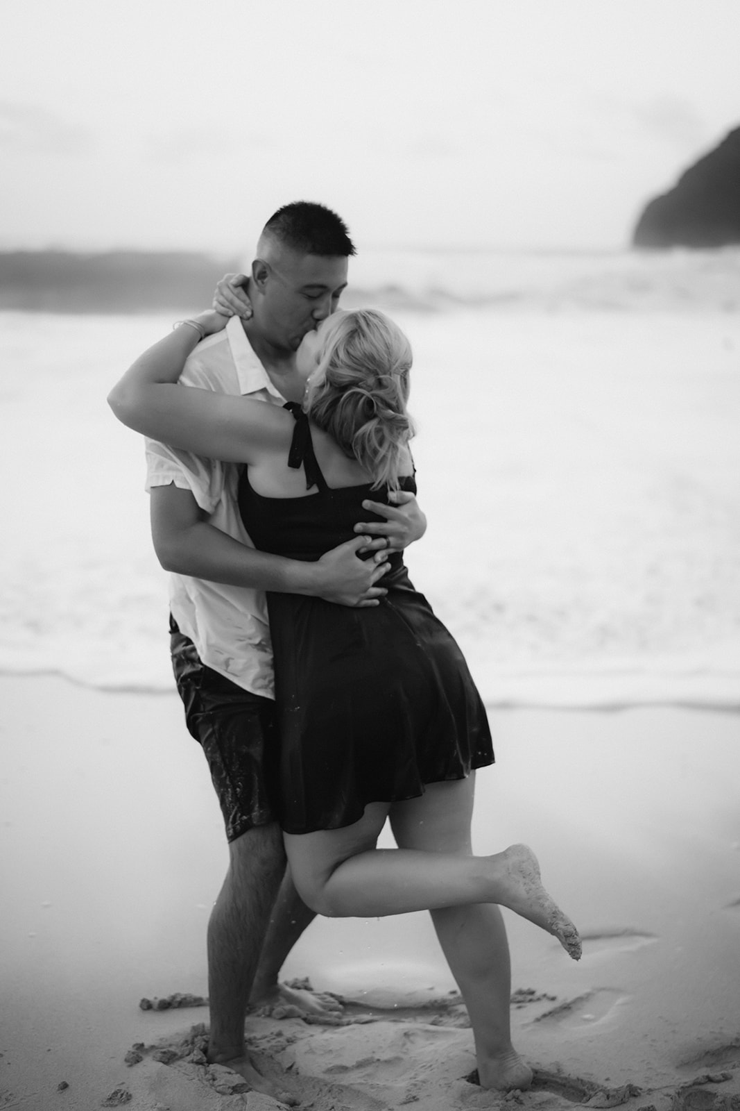 black and white photo man and woman kissing hugging makapuu beach