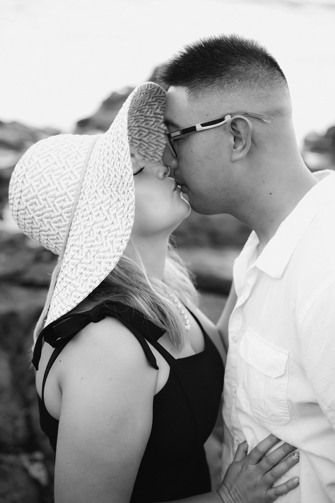 man and woman with sunhat kissing black and white