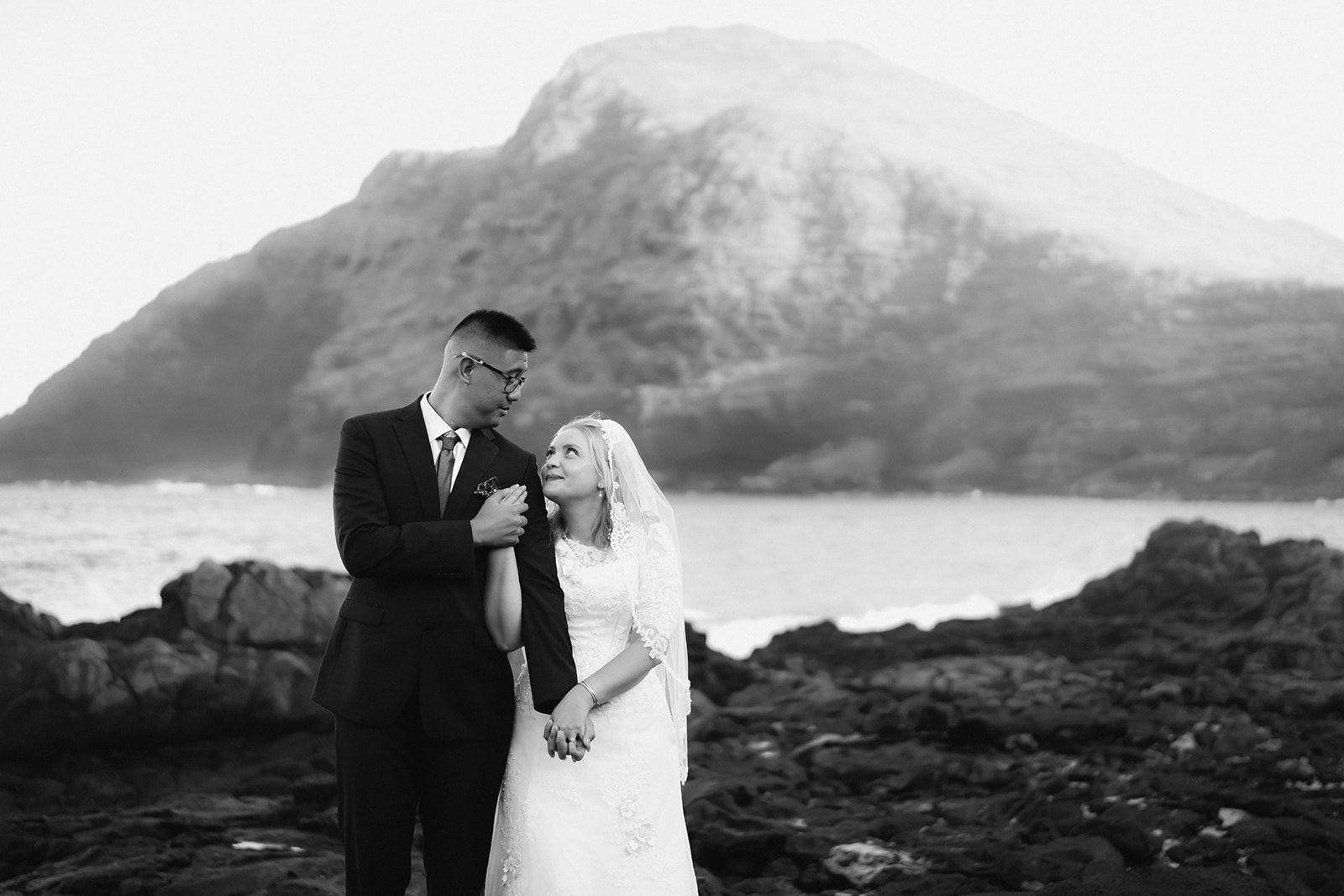 black and white photo couple holding hands looking into each others eyes makapuu beach hawaii