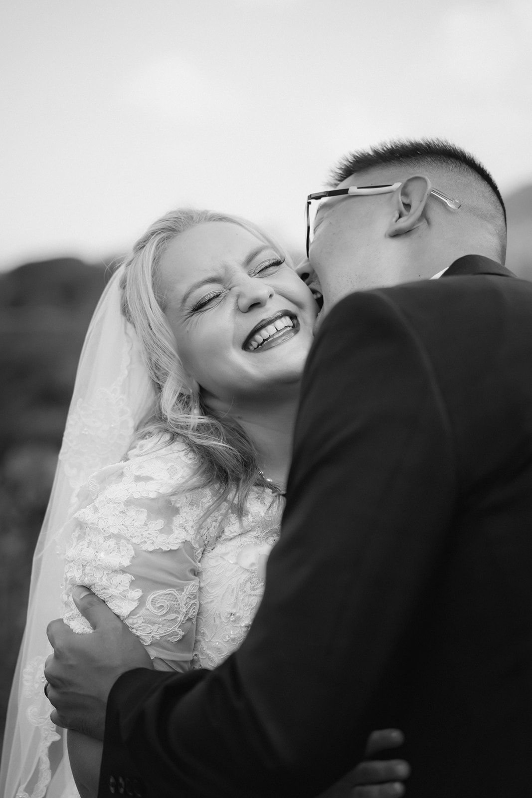 black and white bride smiling husband kissing cheek laughing