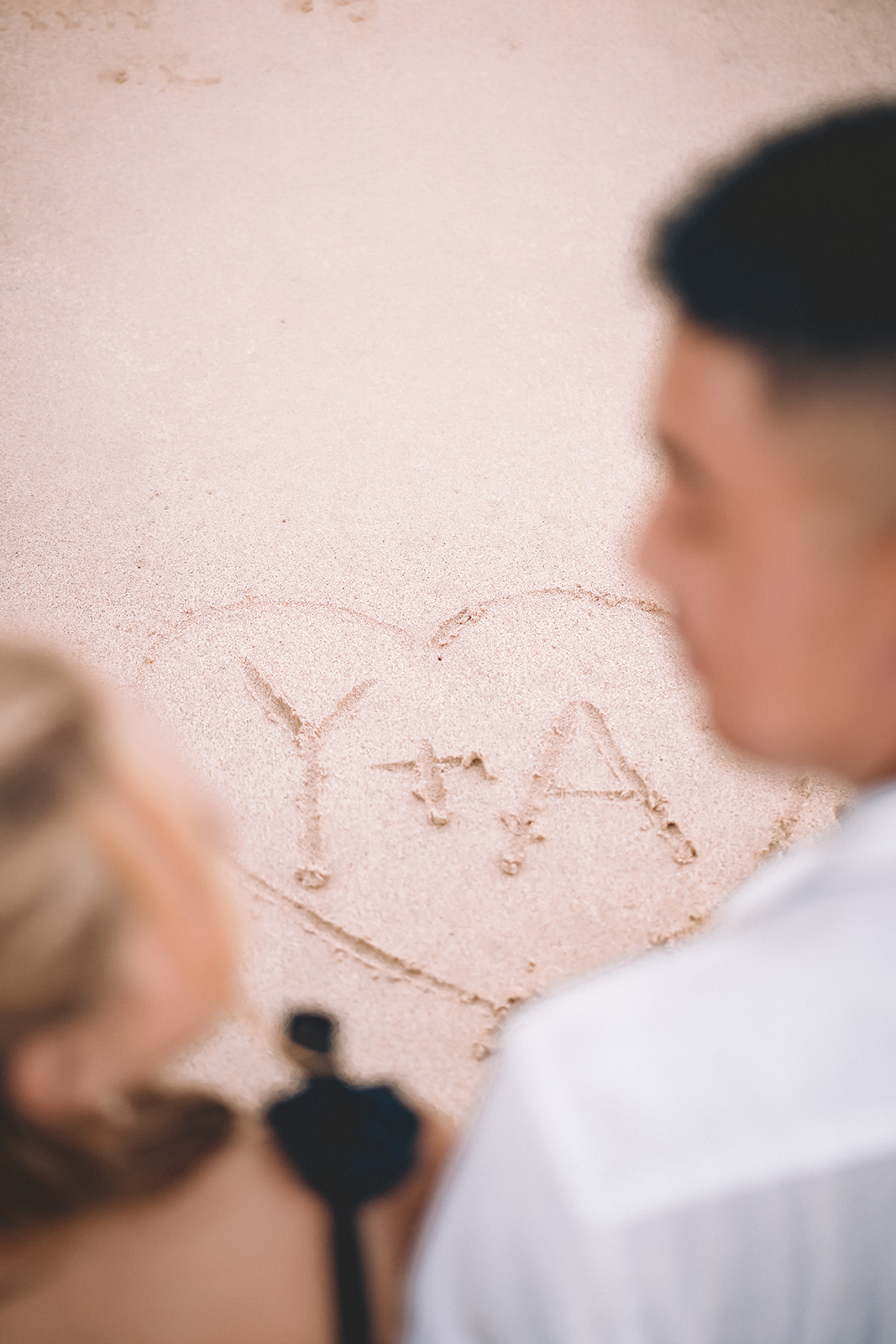 man and woman write y+a in sand makapuu beach