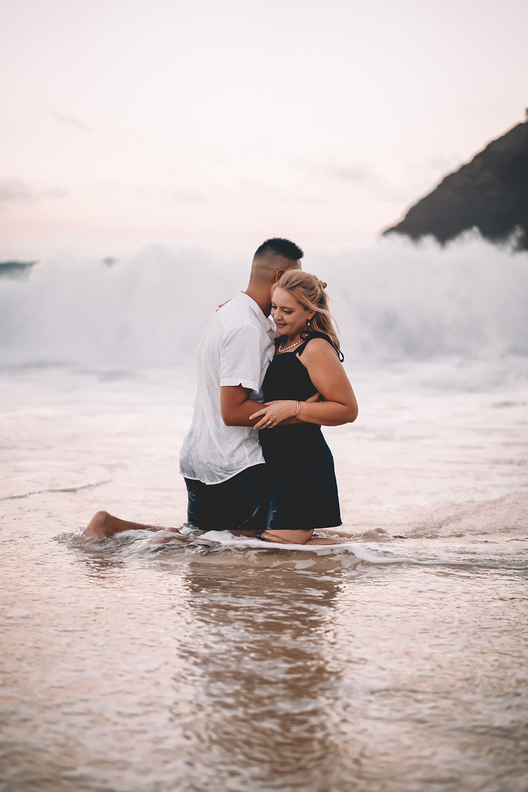 woman and man kneeling hugging at shoreline