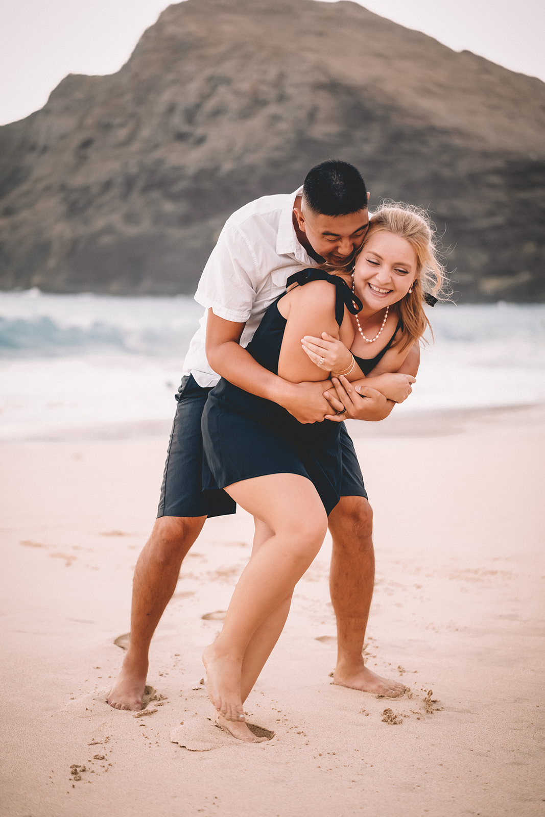 man hugging woman laughing smiling makapuu beach