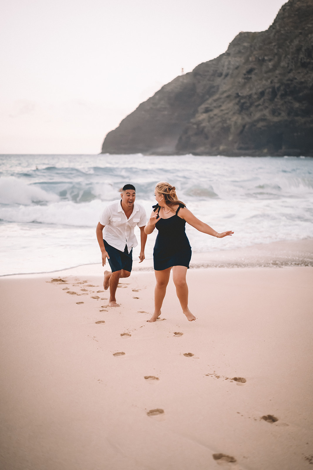 man chasing woman makapuu beach footprints in sand