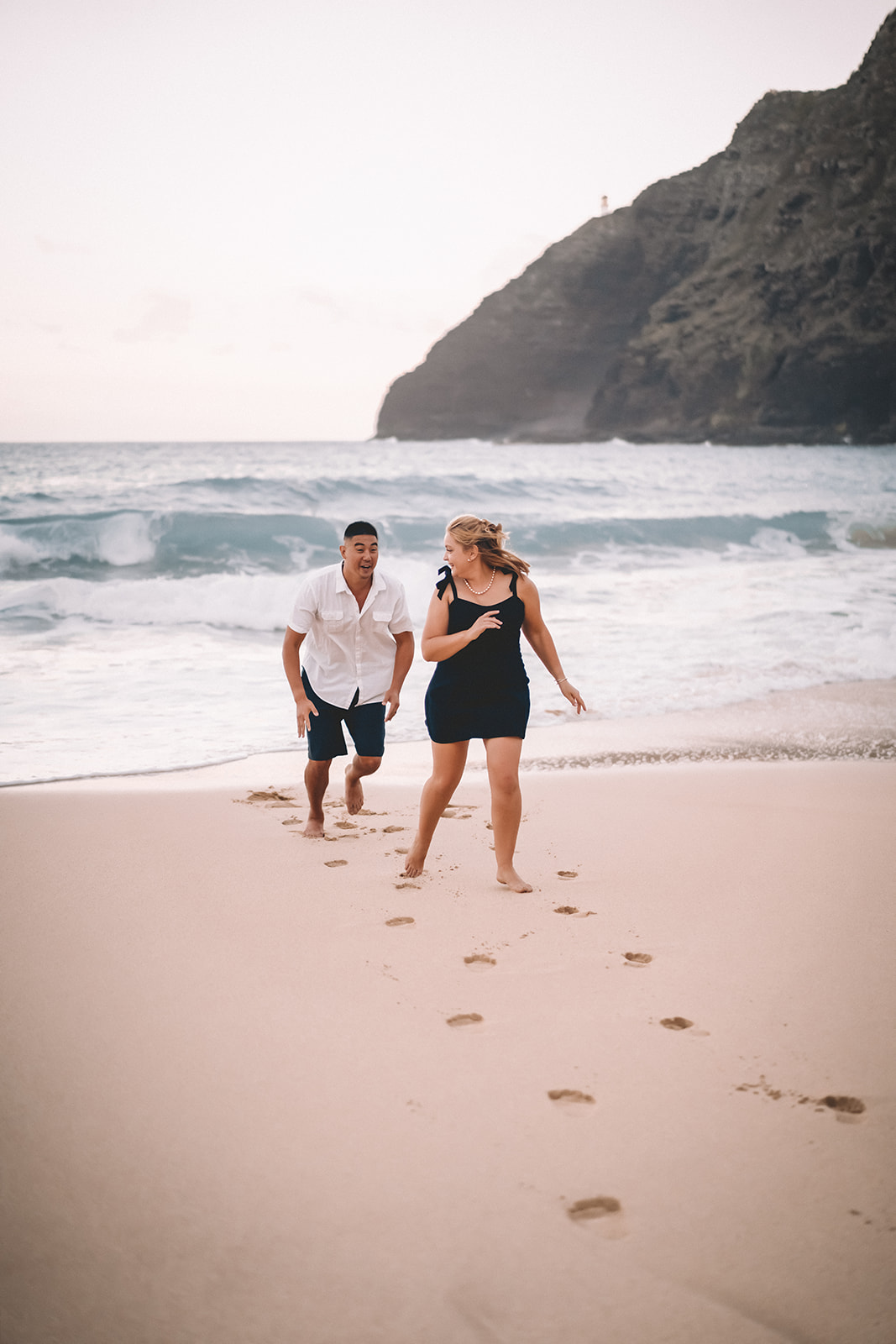 man and woman running out of water sand footprints makapuu beach