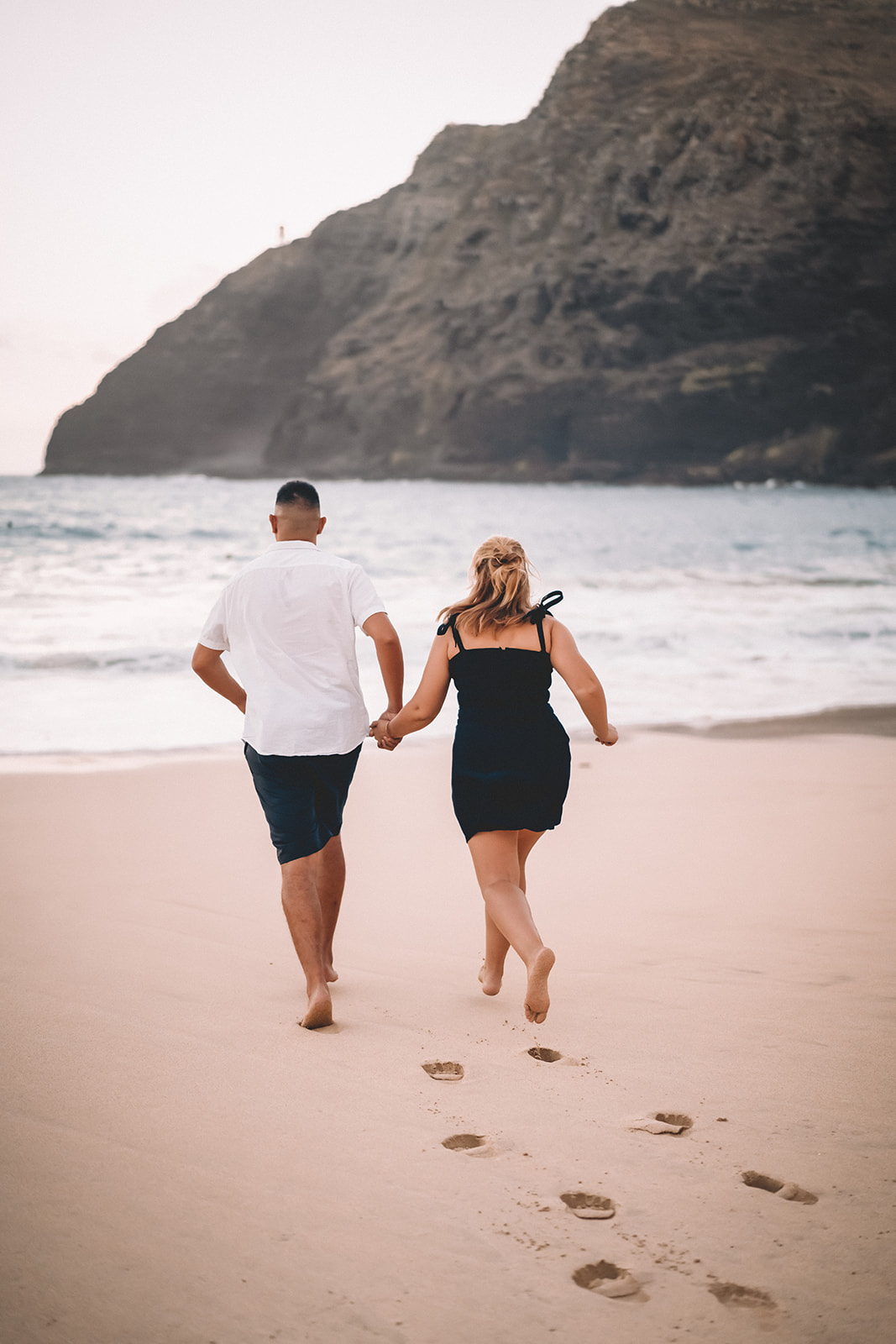 Couple running into Pacific Ocean makapuu beach hawaii