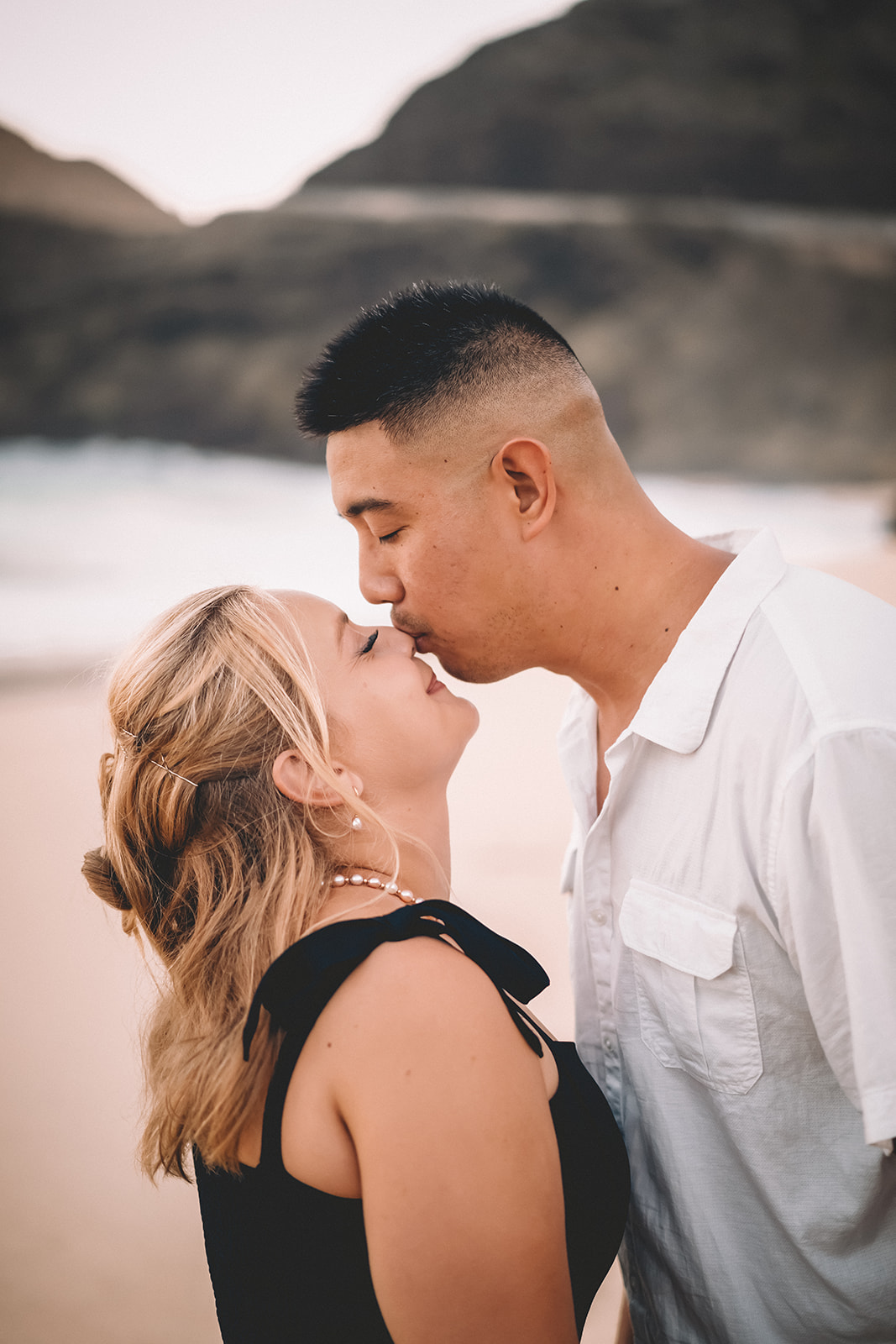 Man kissing fiancée on nose makapuu beach Hawaii engagement