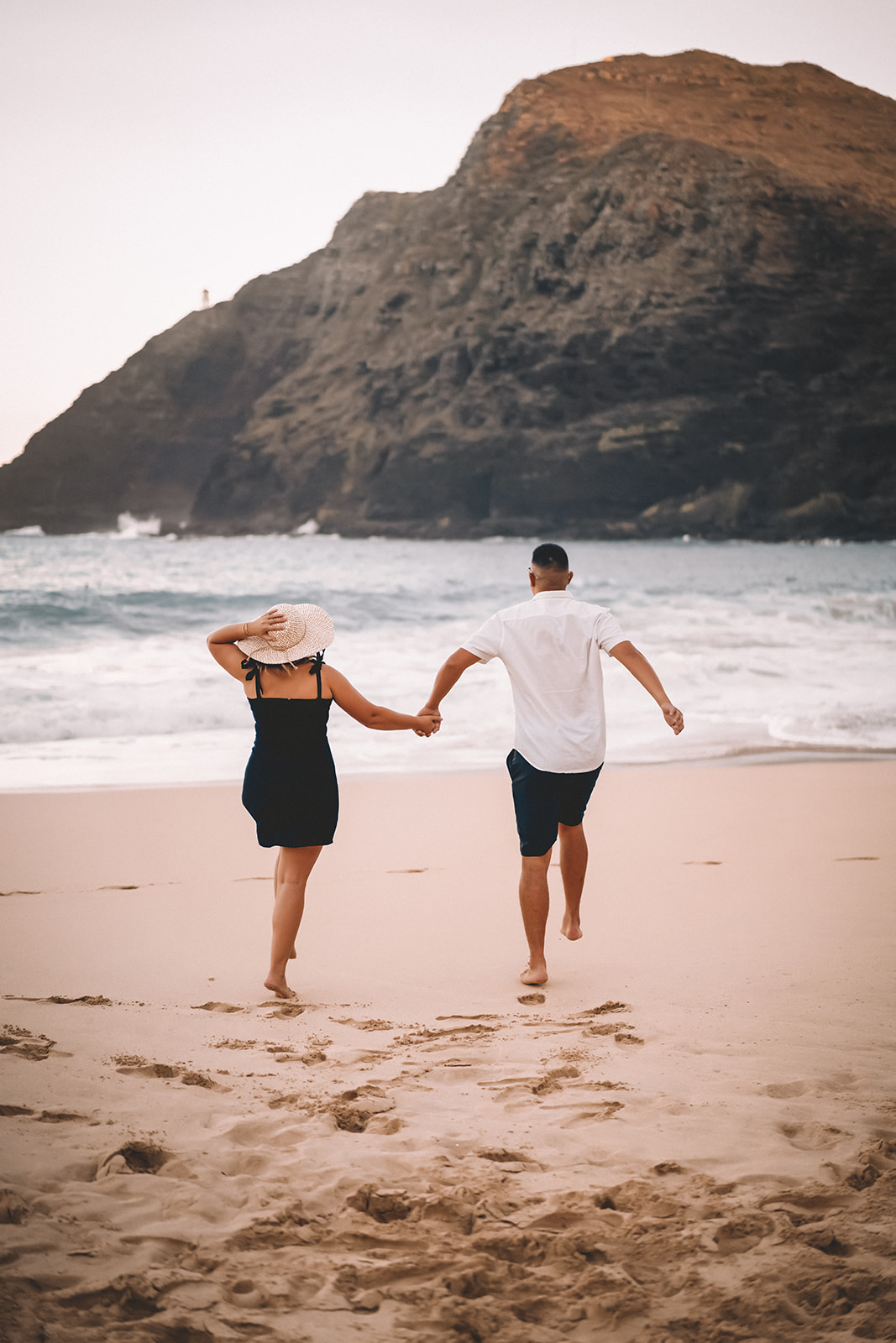 man and woman plafully run across makapuu beach